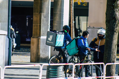 Rear view of people riding bicycle in city