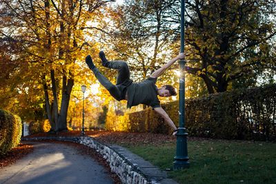 Man hanging on pole in park during autumn