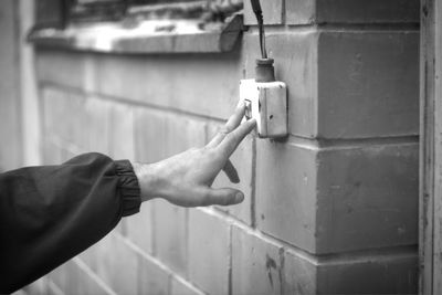 Close-up of hand holding metal against wall