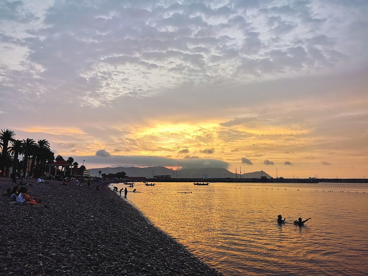 PEOPLE ON BEACH AGAINST SKY AT SUNSET