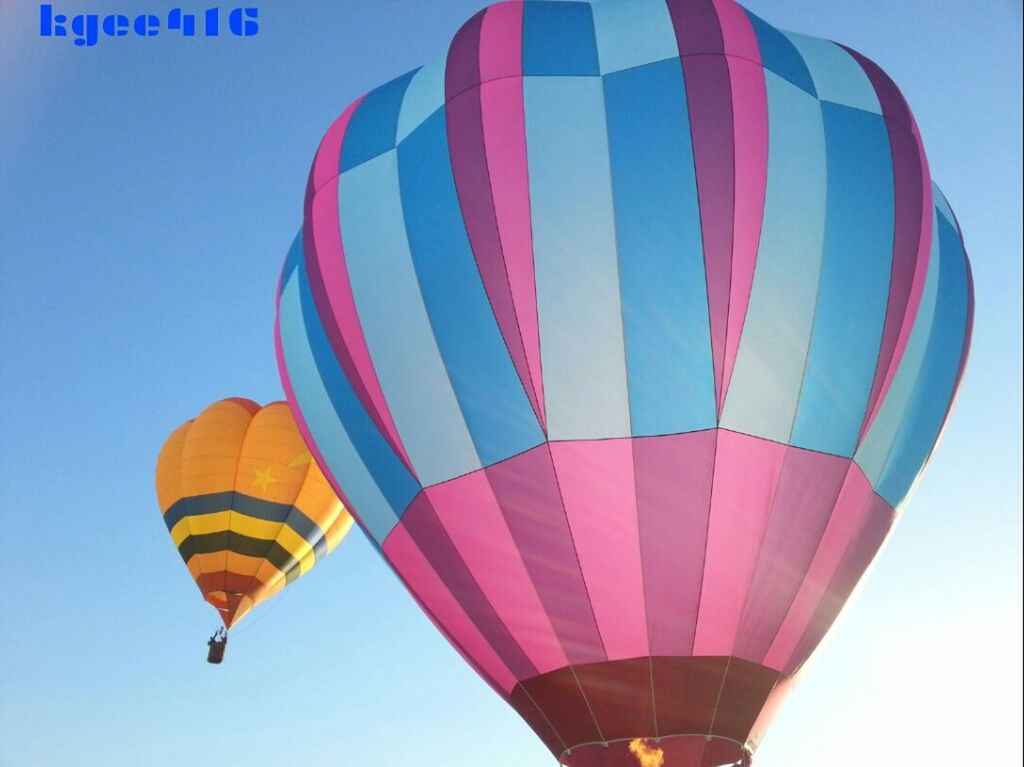 low angle view, multi colored, hot air balloon, mid-air, flying, sky, clear sky, parachute, colorful, balloon, fun, blue, outdoors, arts culture and entertainment, celebration, pattern, day, adventure, patriotism, no people