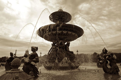 Fountain with sculptures in lake against sky