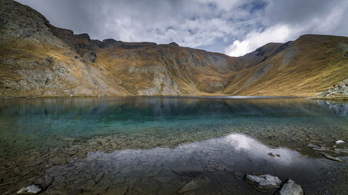 Scenic view of lake by mountains against sky