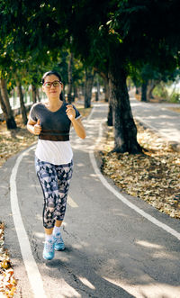 Woman doing yoga on road against trees