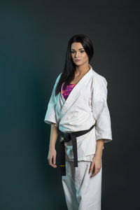 Portrait of karate woman standing against black background