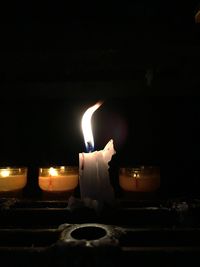 Close-up of burning candle on table in darkroom