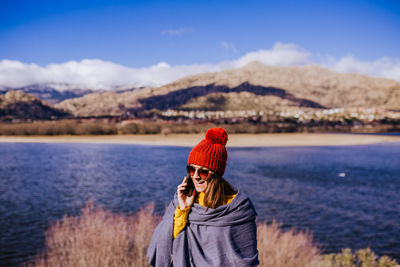 Portrait of young woman standing on snow covered mountain against sky