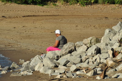 Side view of woman sitting on rocks at beach