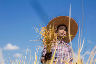 Low angle portrait of woman standing on field against sky