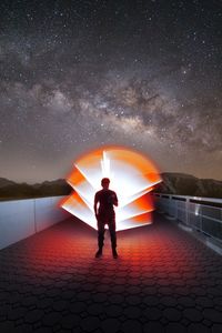 Rear view of man standing against sky at night