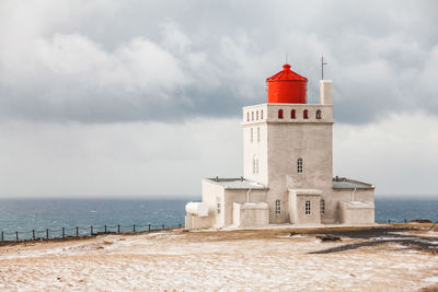 Lighthouse on beach against sky