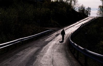 Rear view of man walking on road