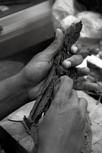 Cropped hands holding making cigar in workshop