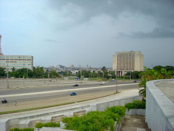 Road by buildings in city against sky