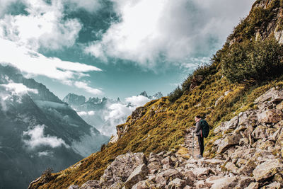 Rear view of man climbing on mountain against sky