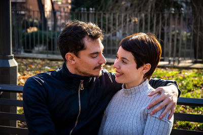 The young couple is sitting on a bench in the park in rome. 