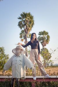 Woman standing by tree on field against clear sky