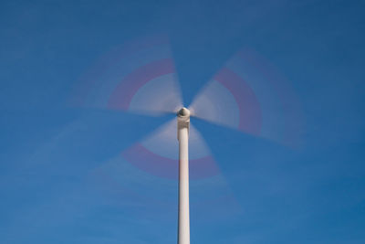 Low angle view of wind turbine against blue sky