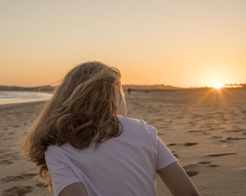Rear view of woman looking at sea at sunset