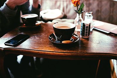 Coffee cup by smart phone on wooden table