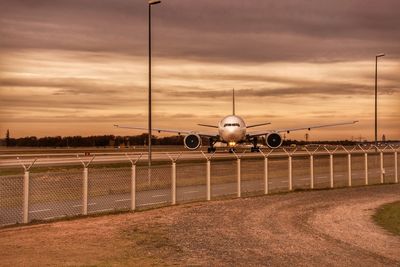 Airplane on field against sky during sunset