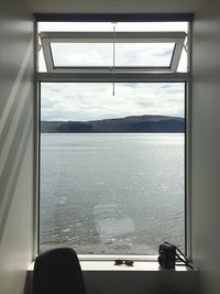 Close-up of window by sea against sky