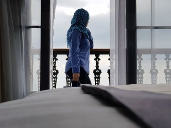 Side view of woman standing in balcony against sky