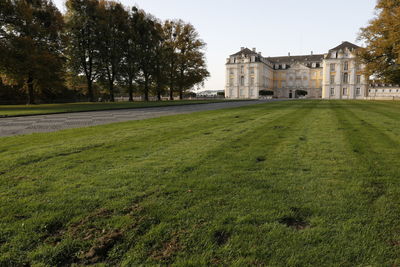 Lawn by building on field against sky