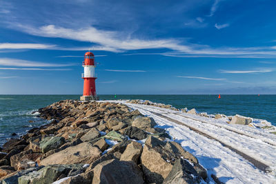 Lighthouse by sea against sky