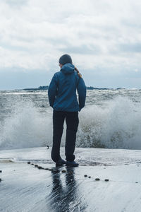 Rear view of man standing on snow covered landscape against sky