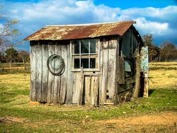 Old abandoned house on field against sky