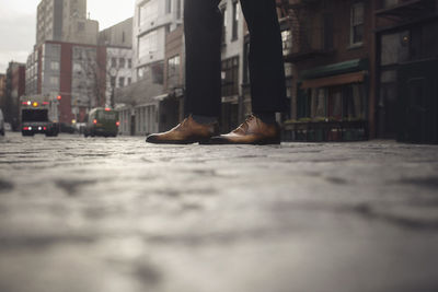 Low section of man standing on street against buildings