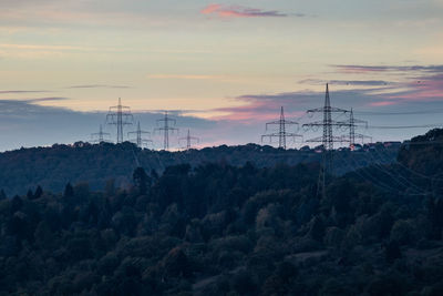 Electricity pylon on land against sky during sunset