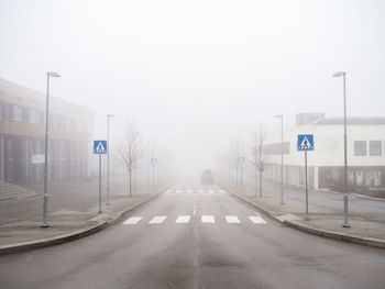 Road amidst buildings in foggy weather