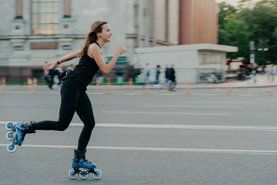 Full length of woman skateboarding on road in city