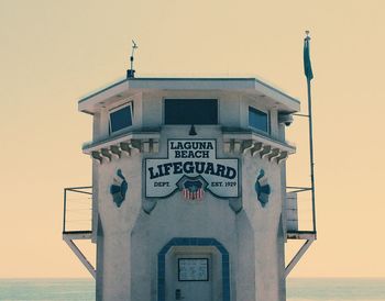 Information sign by sea against clear sky