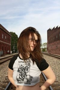 Portrait of young woman standing against buildings