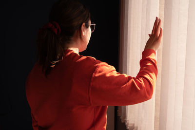 Side view of young woman against wall