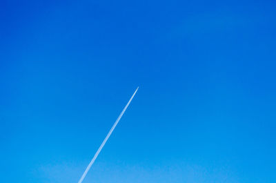 Low angle view of vapor trail against clear blue sky