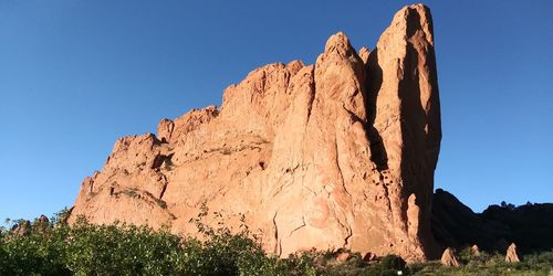 Low angle view of rock formation against clear blue sky