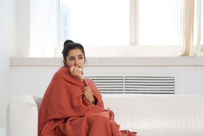 Ill woman looking away while sitting at home