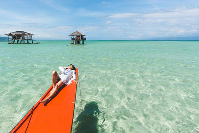 High angle view of mid adult woman relaxing on boat in sea against sky during sunny day