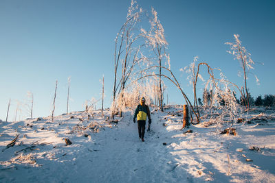 Woman on snow covered field against sky