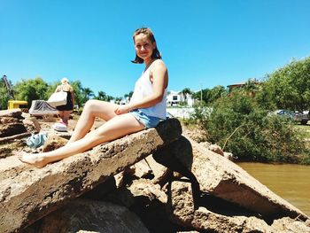 Portrait of smiling woman on rock against sky