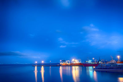 Illuminated dock by sea against sky at night