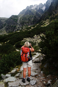 Rear view of girl standing on rock against mountains