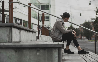 Young man sitting on stepping in an urban space. 