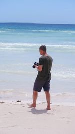 Full length of man photographing on beach