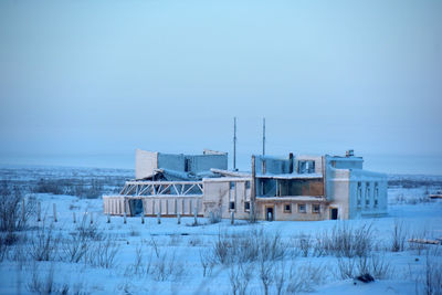 Buildings by sea against clear sky during winter