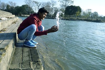 Side view of young man using mobile phone in water